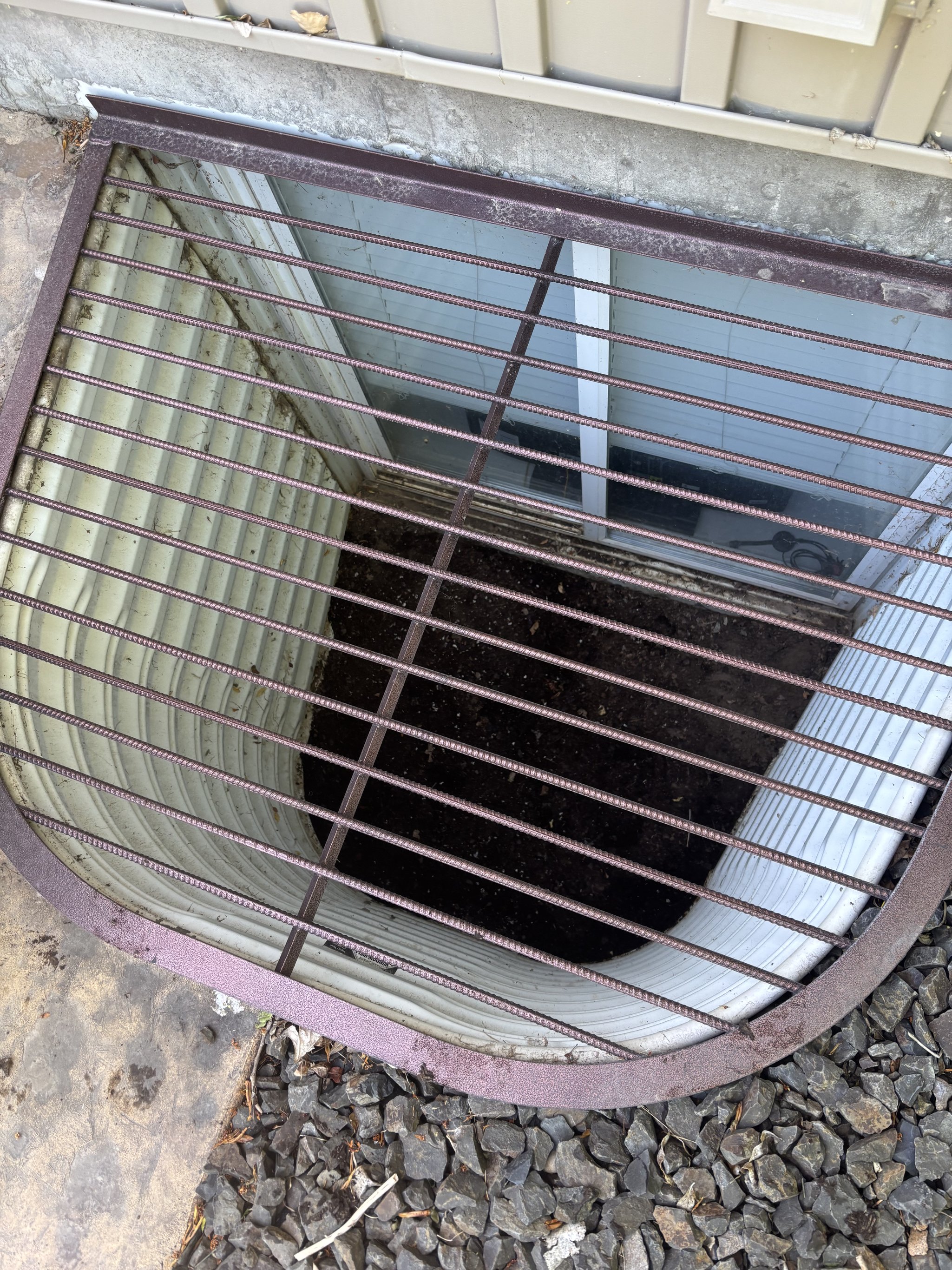 Person cleaning a basement window well